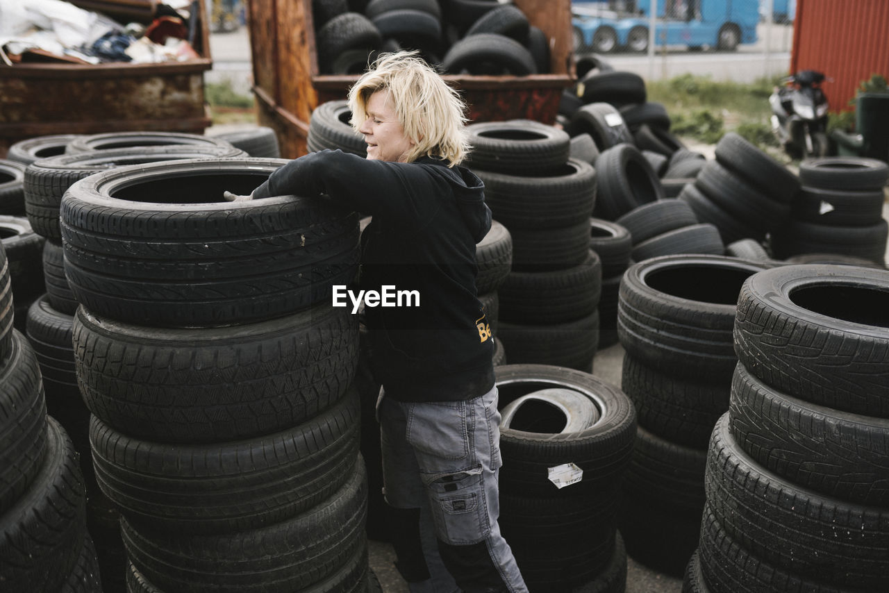 Female mechanic stacking car tires