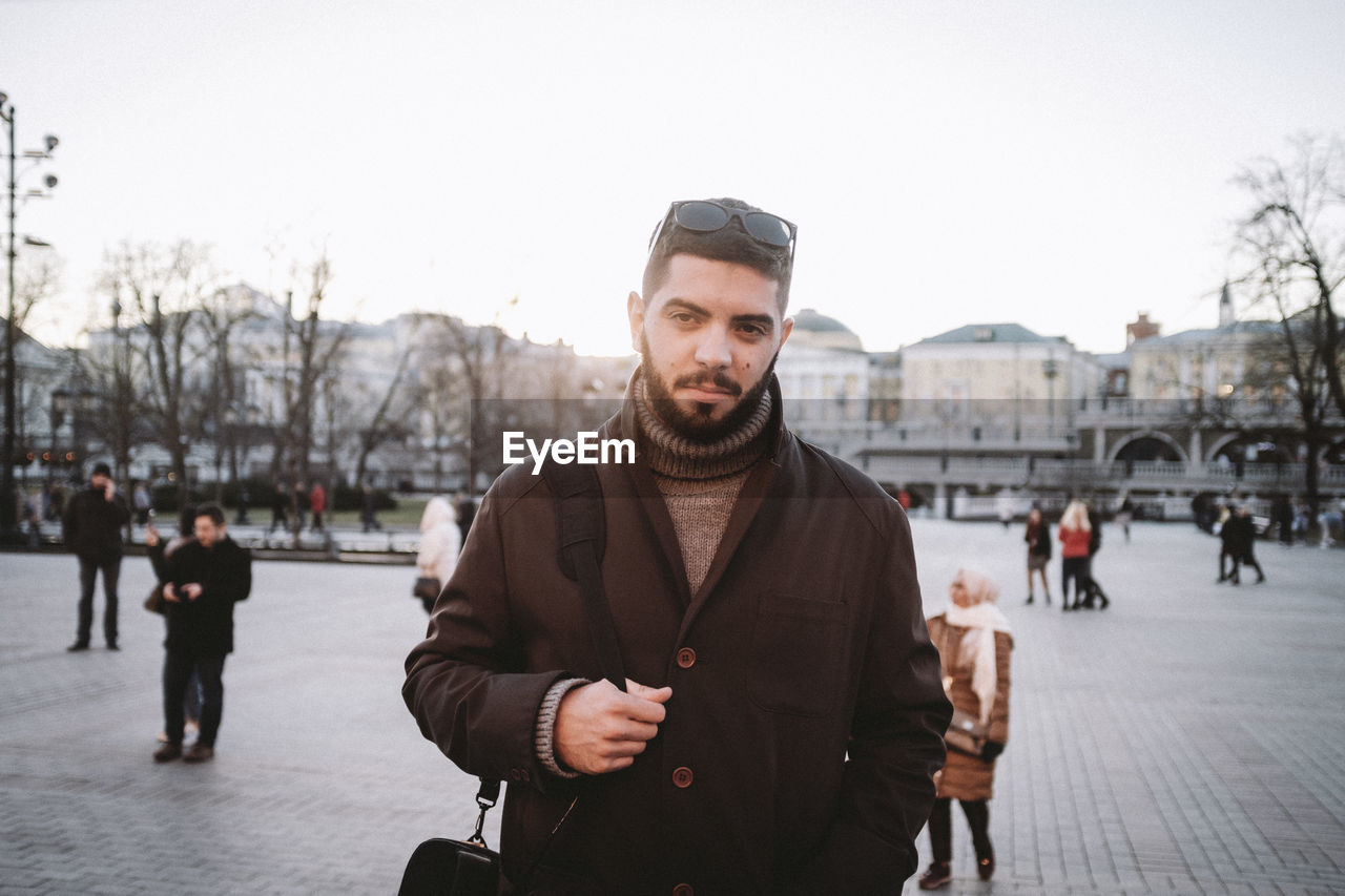 Portrait of young man standing in city during winter