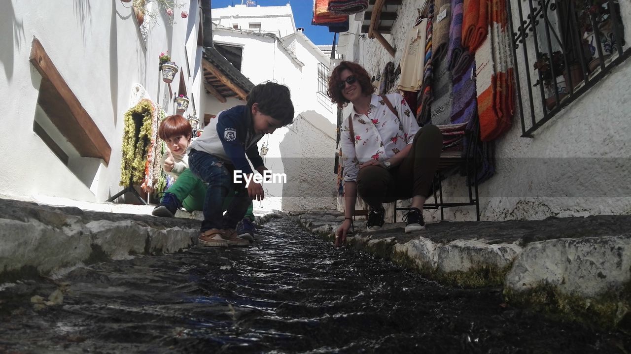 PEOPLE STANDING ON WALL BY BUILDINGS