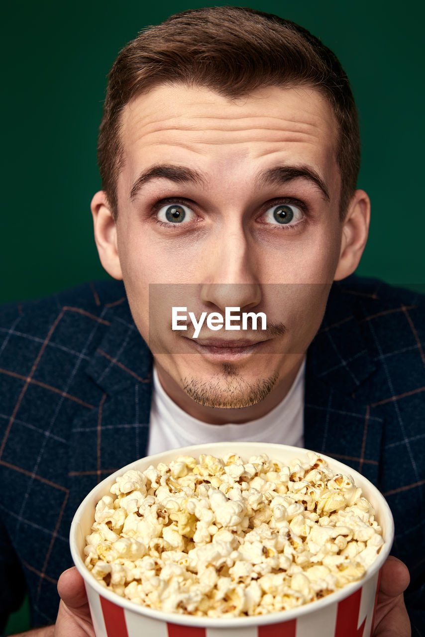 popcorn, food and drink, portrait, one person, food, men, kettle corn, adult, looking at camera, studio shot, snack, indoors, eating, emotion, young adult, holding, facial expression, person, healthy eating, human face, movie, meal, fun, wellbeing, lifestyles, positive emotion, bowl, headshot, front view