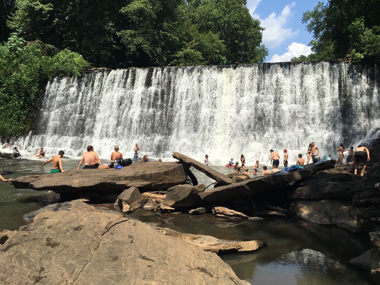 PEOPLE ENJOYING IN WATER AGAINST SKY