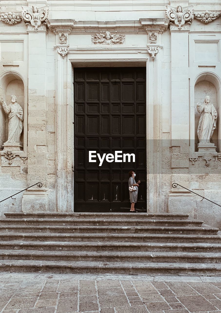 Woman standing by door of historic building