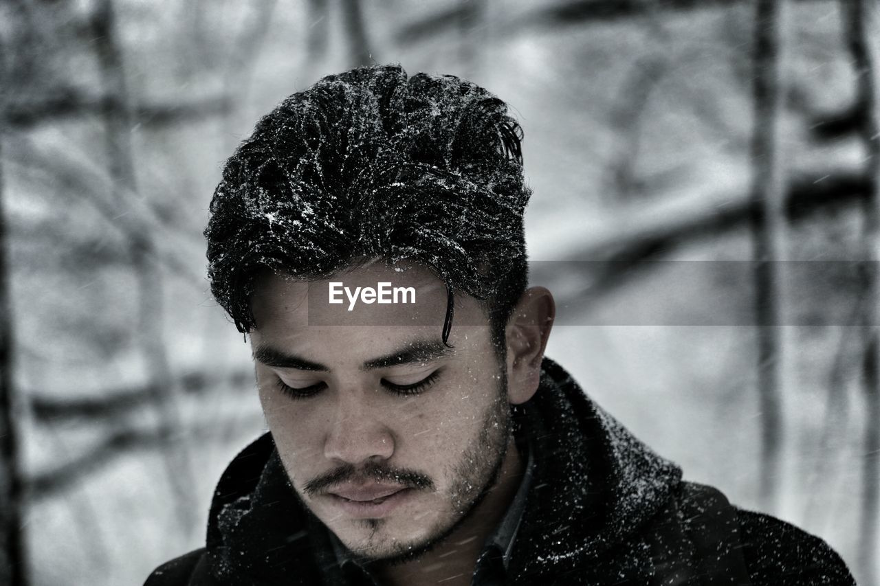 Close-up of man looking down during snowfall