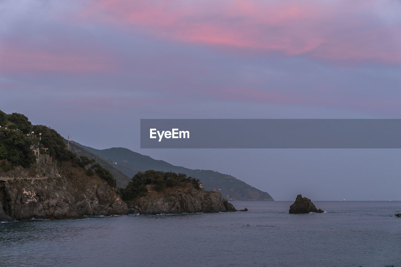 Breathtaking view of rippling sea and rocky cliffs located against cloudy sundown sky in nature