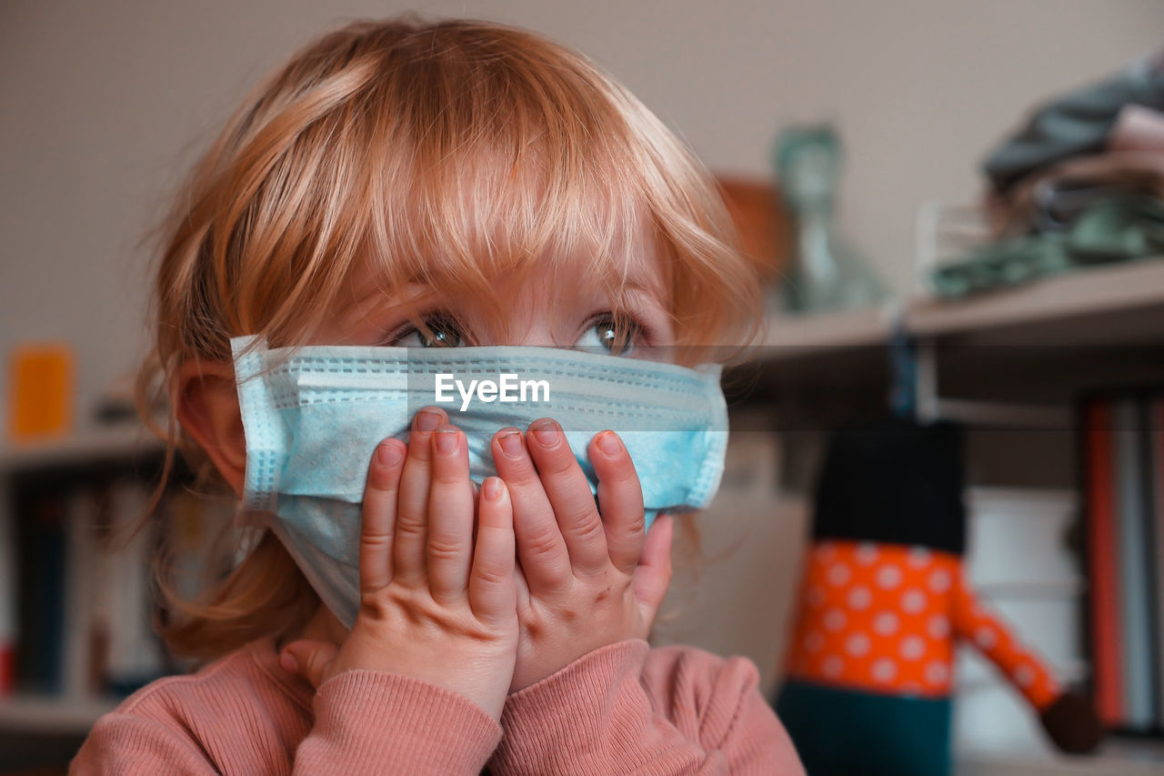 Close-up of cute girl wearing mask at home