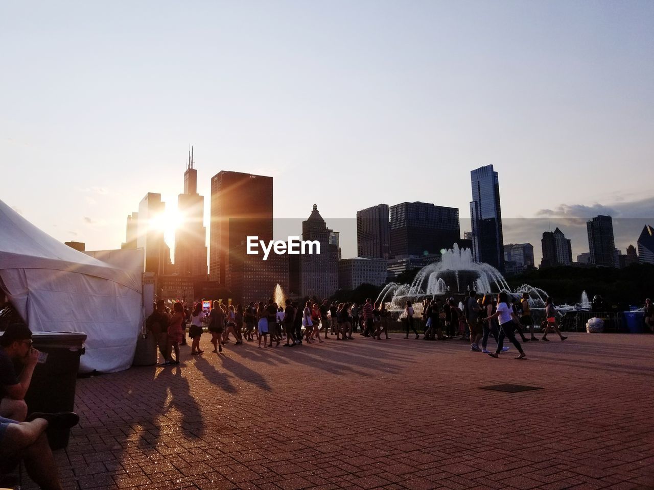 PEOPLE WALKING IN CITY AGAINST SKY DURING SUNSET