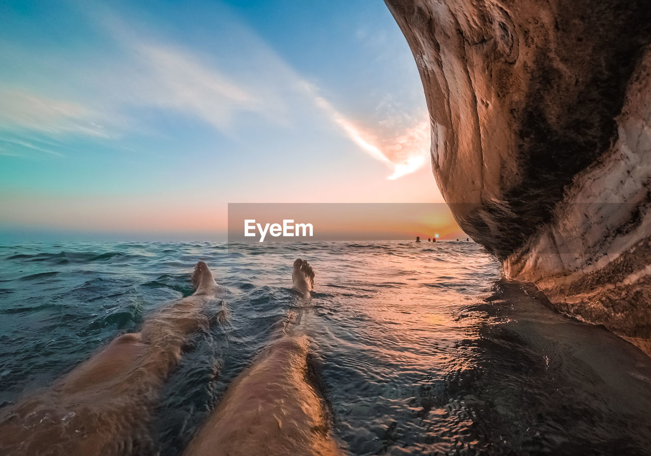 A man lies in the water under white rocks in abkhazia at sunset