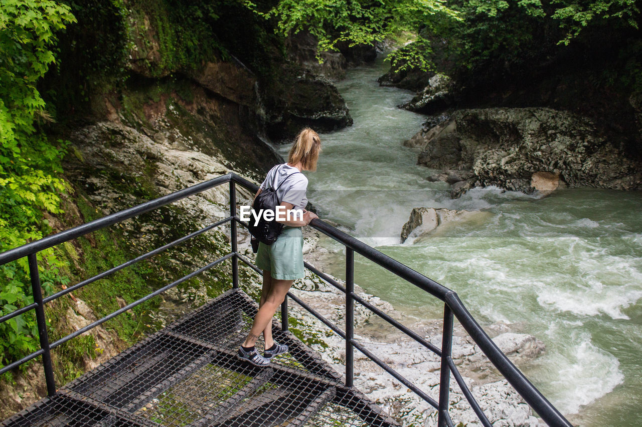 High angle view of woman standing on bridge over river in forest