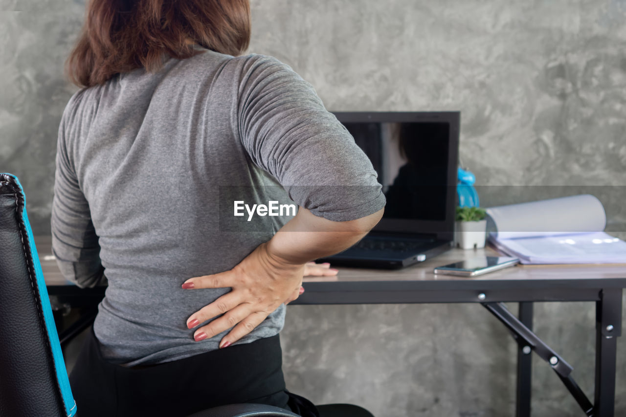 Business woman suffering from office syndrome having lower back pain sitting on chair