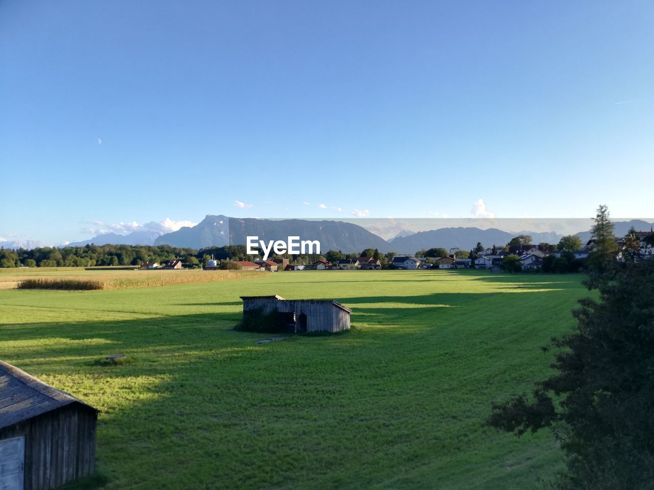 sky, landscape, grass, scenics - nature, environment, plant, nature, mountain, green, land, beauty in nature, house, architecture, building, built structure, building exterior, tranquility, tranquil scene, no people, sport venue, blue, field, clear sky, day, rural scene, mountain range, tree, residential district, golf, non-urban scene, outdoors, sports, travel destinations, golf course, idyllic, farm, water, agricultural building, hut, agriculture, sunny, rural area, grassland, meadow, leisure activity, cloud, travel, sunlight