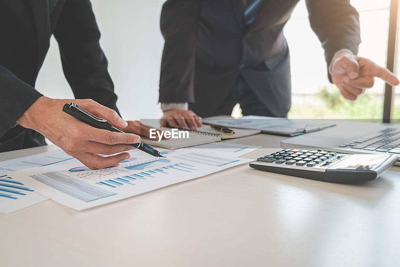 Midsection of business people working on table