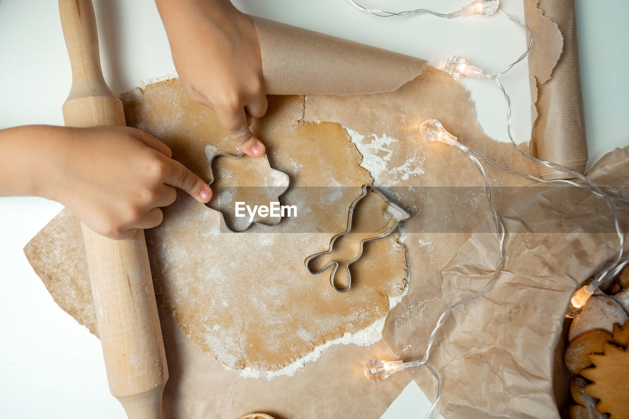 The child's hands make cookies from dough with a mold, the rolling pin lies near the dough with 
