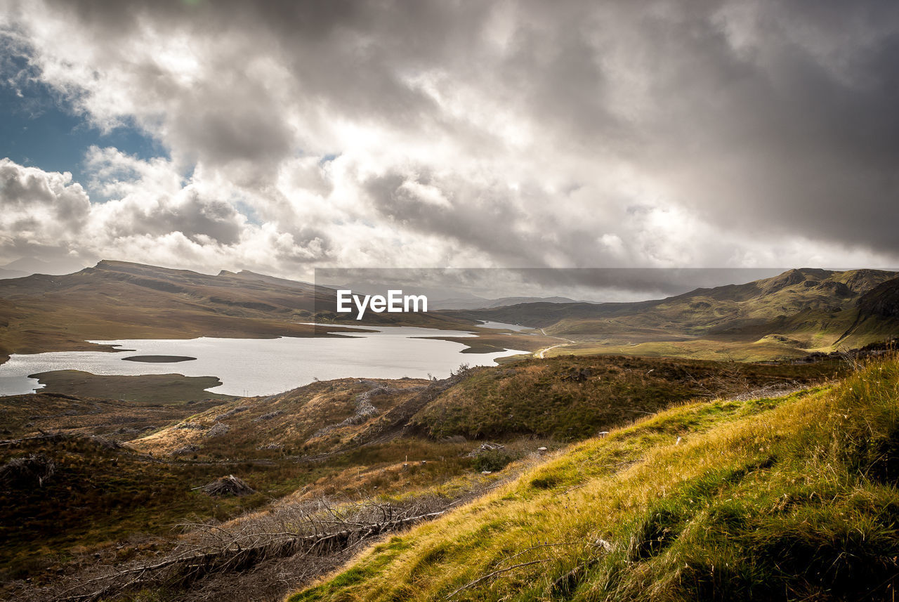 Scenic view of lake and mountains against cloudy sky