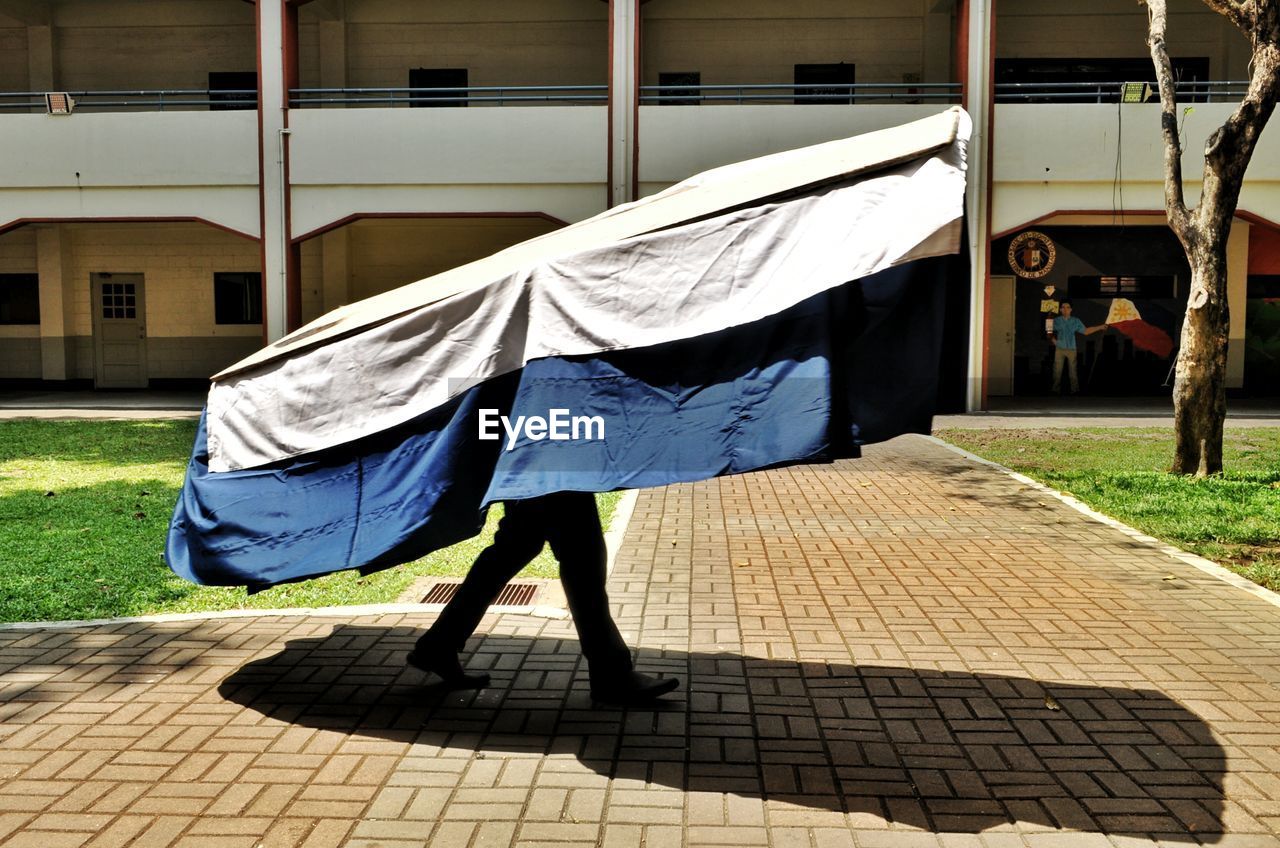 Man carrying fabric material against built structure