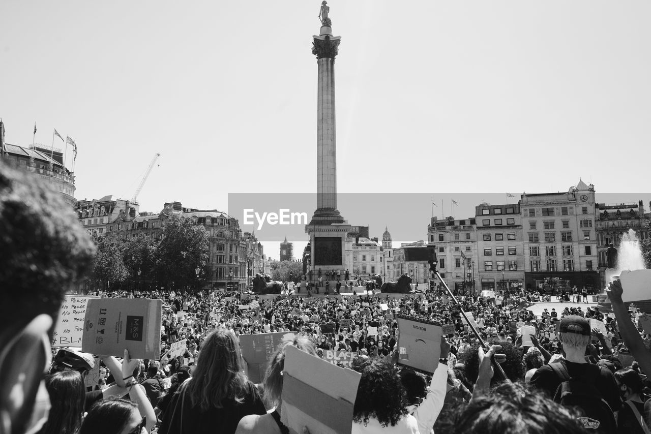GROUP OF PEOPLE IN FRONT OF BUILDINGS IN CITY