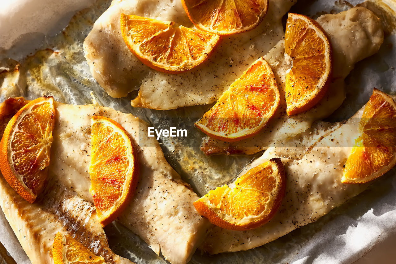 Cod fish fillet with oranges on baking paper. seafood, healthy eating. natural light.