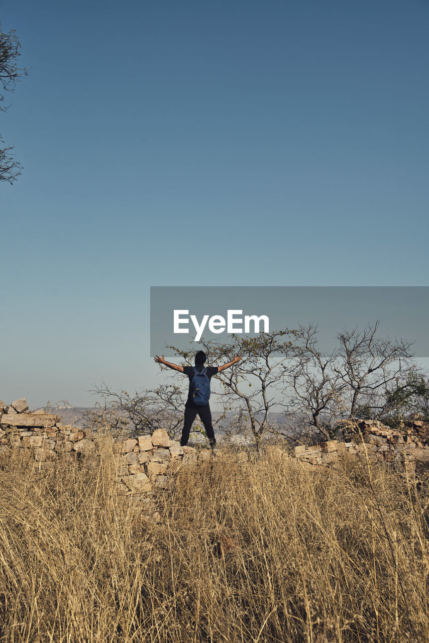 FULL LENGTH OF MAN STANDING ON FIELD AGAINST CLEAR BLUE SKY