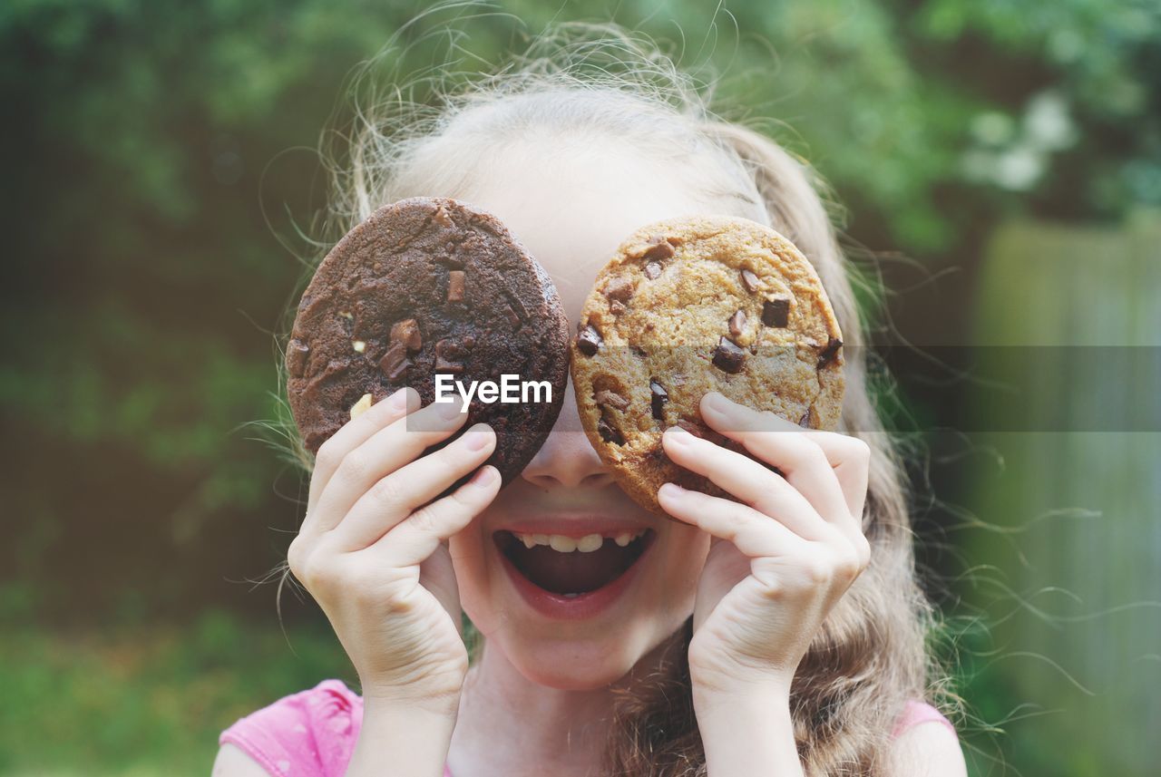 Close-up of cut girl holding cookies while standing outdoors