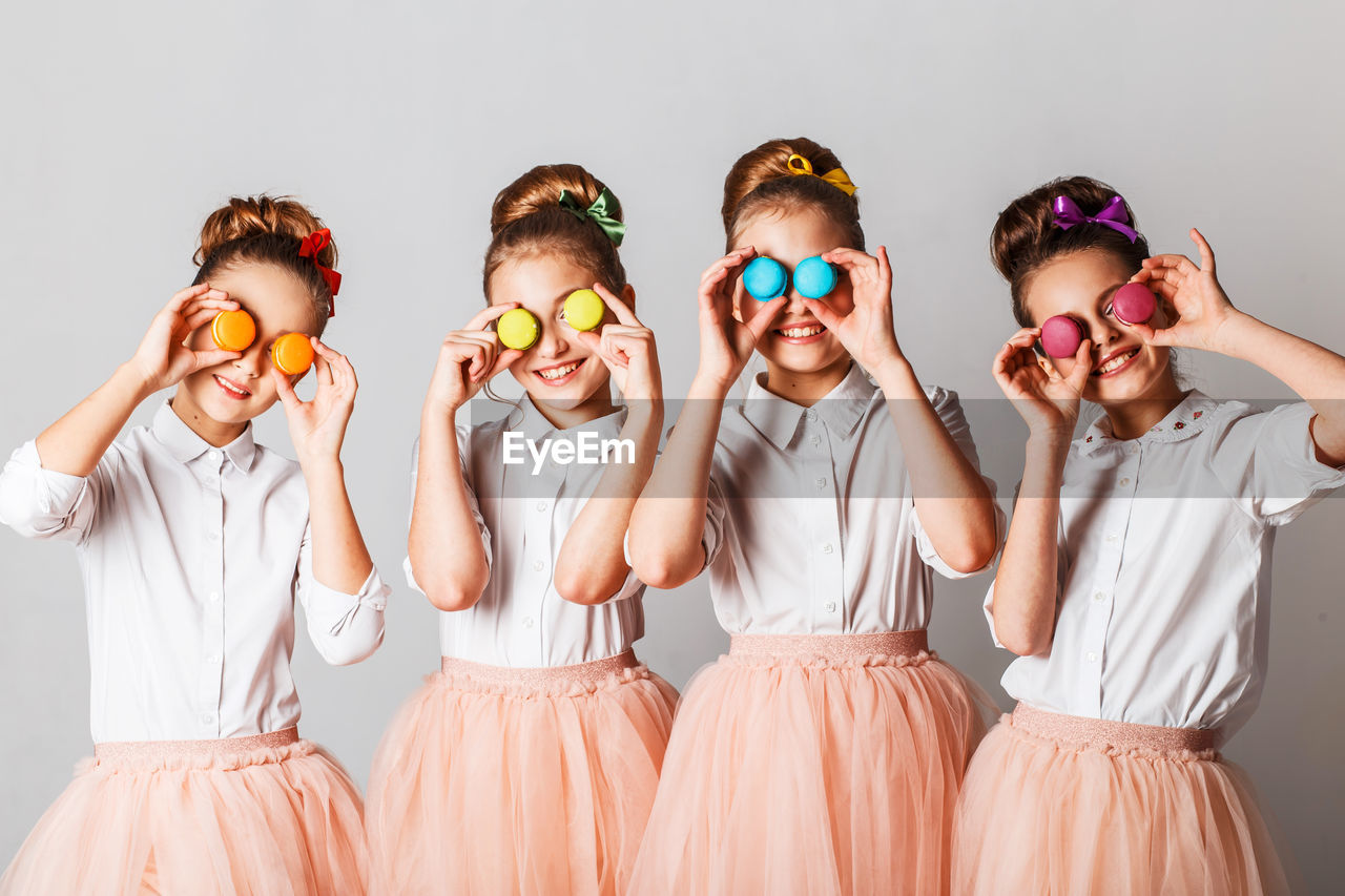 Girls holding colorful macaroons against white background