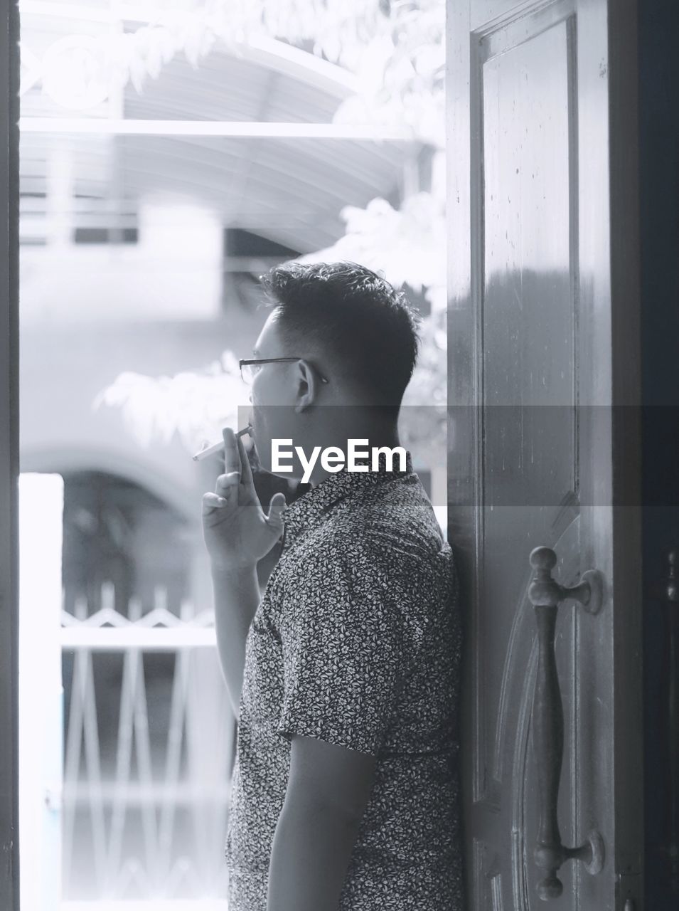 Side view of man smoking cigarette at doorway