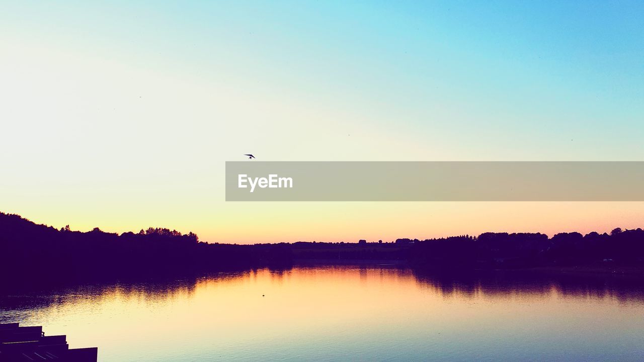 SCENIC VIEW OF LAKE AGAINST CLEAR SKY AT SUNSET