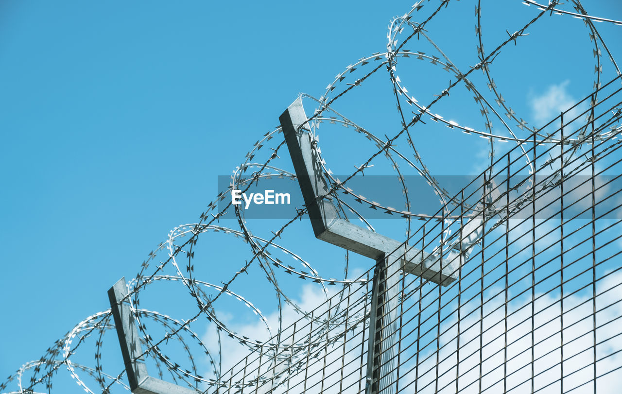 Metal fence against clouds and blue sky.