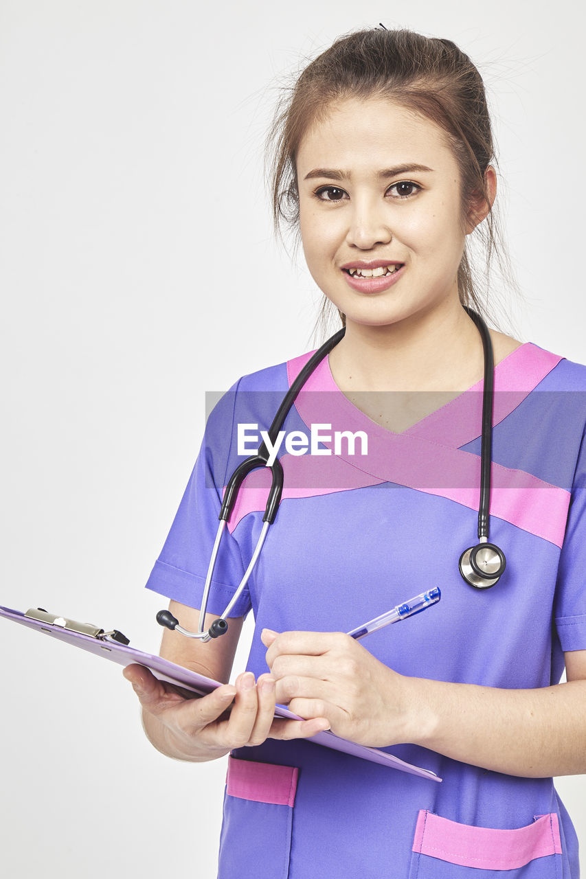 Portrait of nurse standing against white background