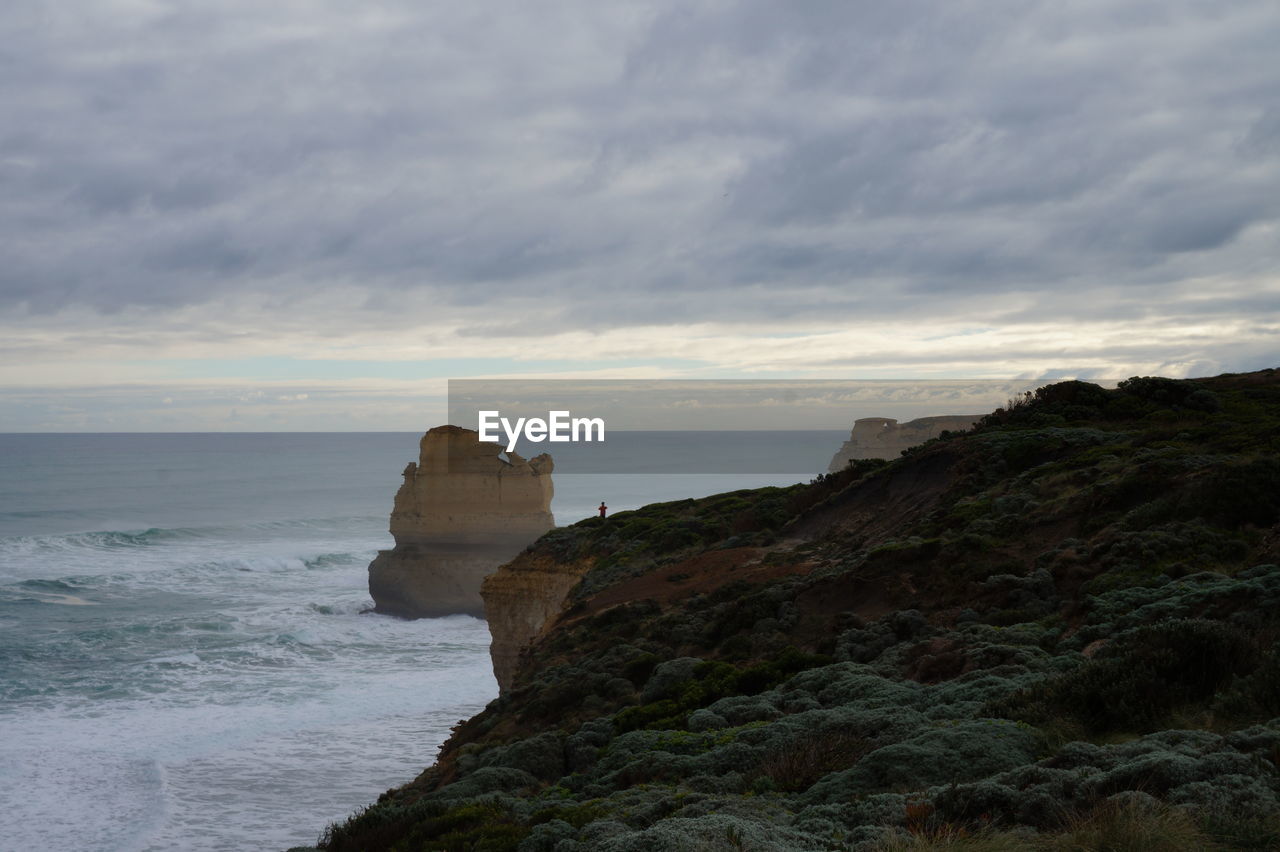 Scenic view of cliff by sea against sky