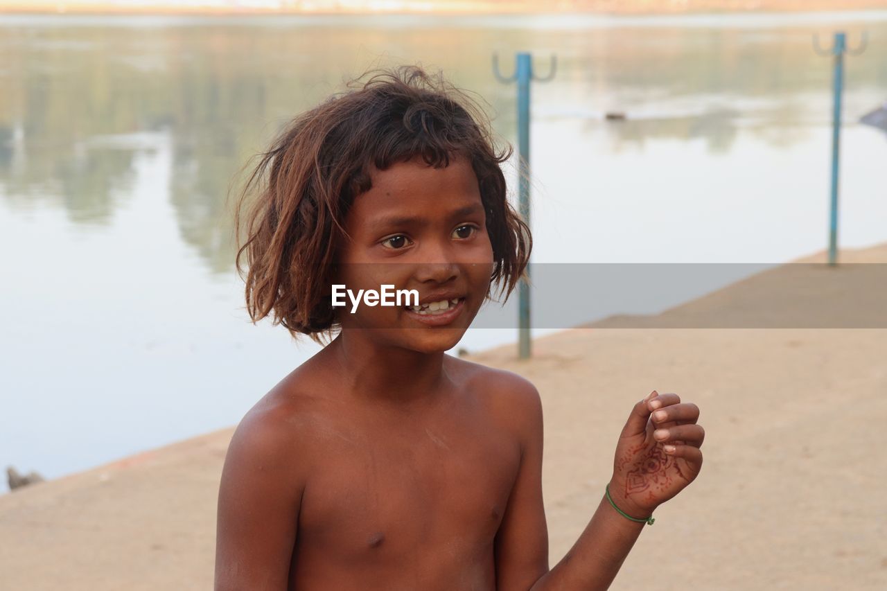 Smiling shirtless girl standing at beach