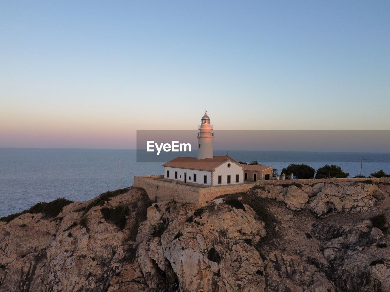 Lighthouse by sea against clear sky