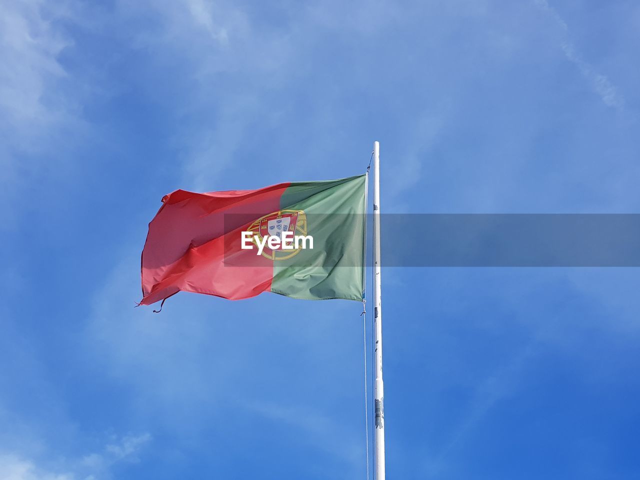 Flag of portugal fluttering blue sky