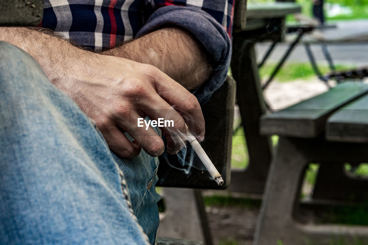 Midsection of man smoking cigarette