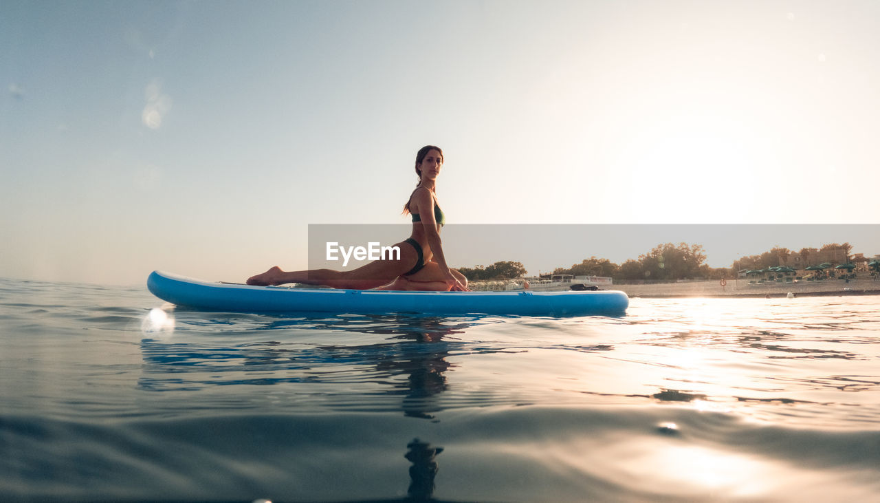 Exercises on a paddle sup board in the ocean at sunrise