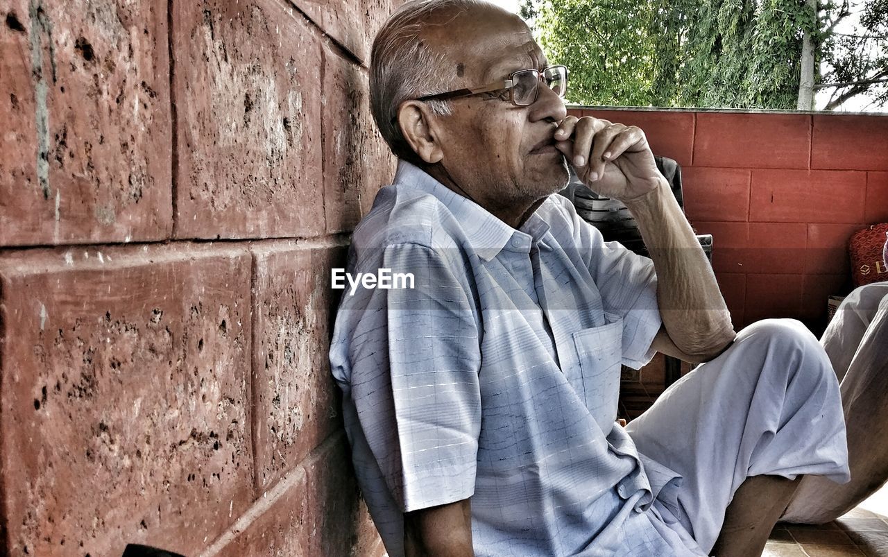 Thoughtful senior man leaning on wall in balcony