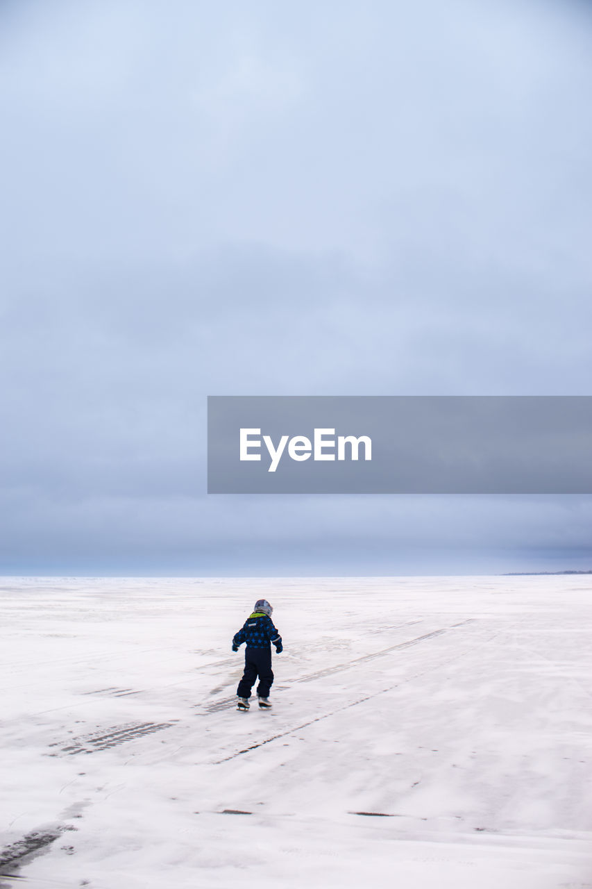 Rear view of person ice-skating on frozen lake peipus against sky