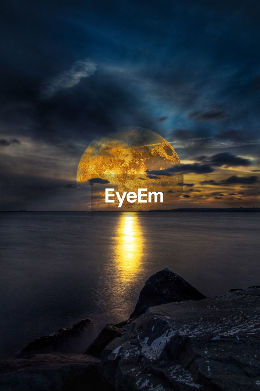 SCENIC VIEW OF ROCKS AT BEACH AGAINST SKY DURING SUNSET