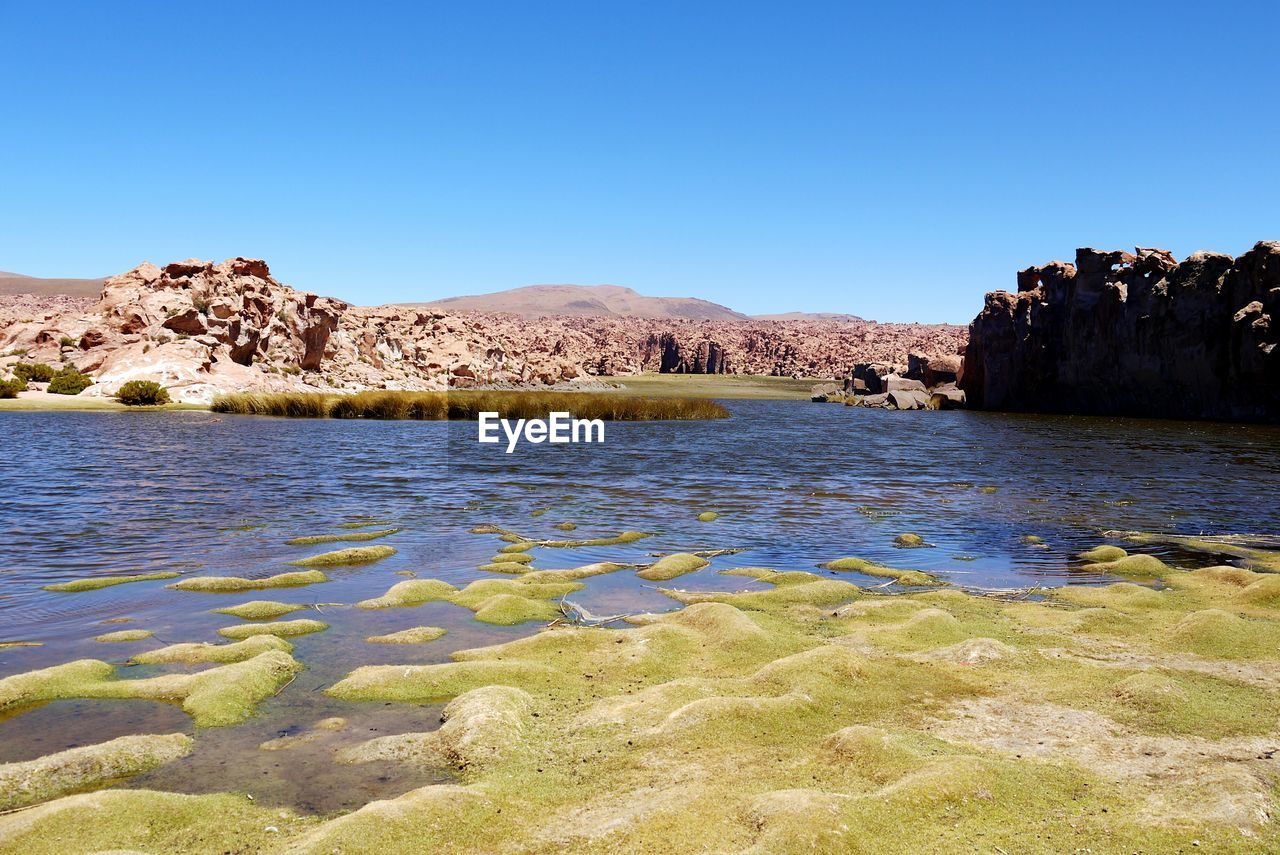 RIVER IN FRONT OF ROCKY MOUNTAINS AGAINST CLEAR BLUE SKY