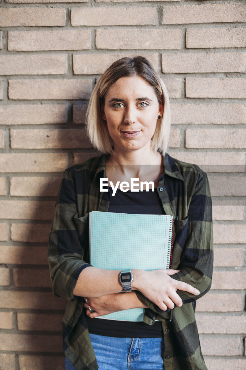 Portrait of woman student on brick wall