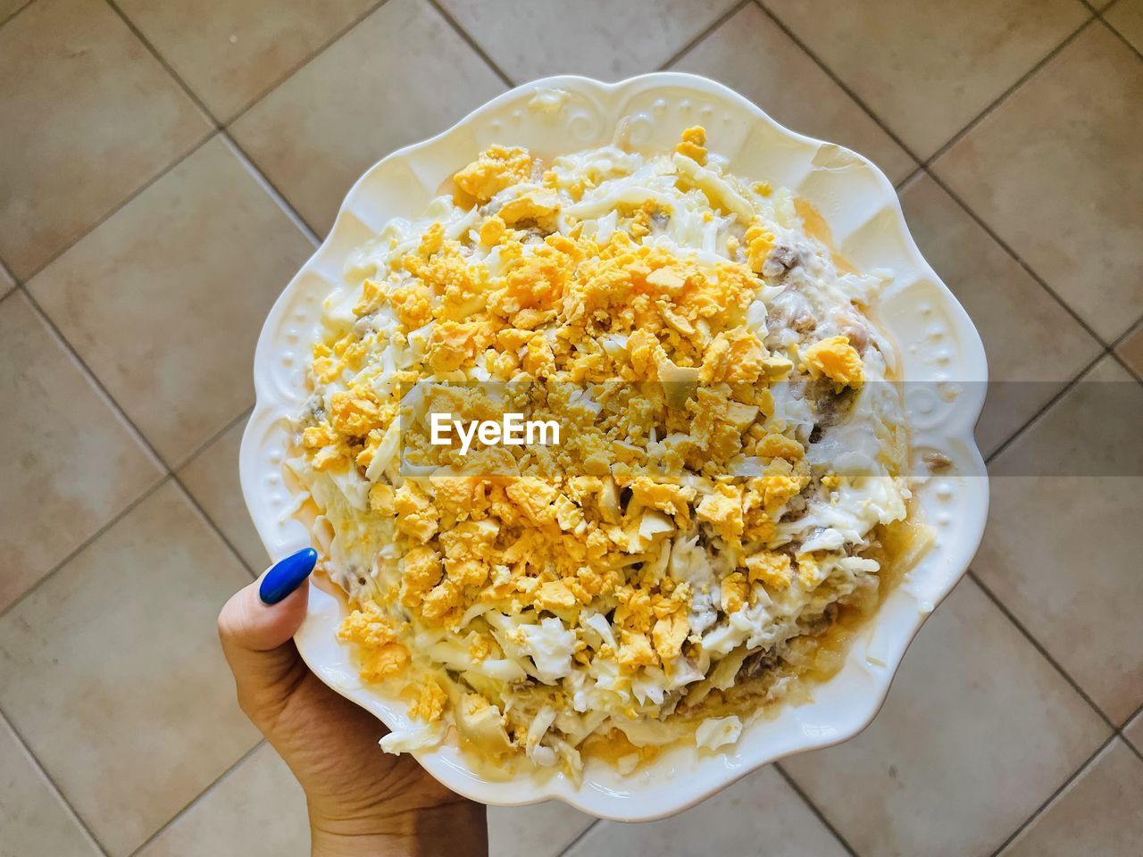 food, food and drink, hand, high angle view, yellow, dish, snack, one person, tiled floor, kettle corn, tile, flooring, holding, freshness, personal perspective, lifestyles, healthy eating, cuisine, indoors, directly above, produce, wellbeing, italian food, dairy, bowl, popcorn