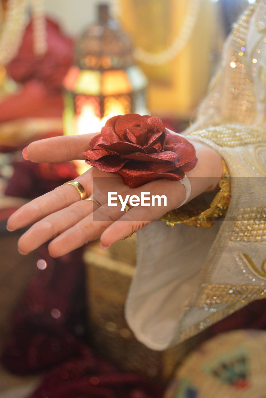Cropped image of bride holding artificial rose 