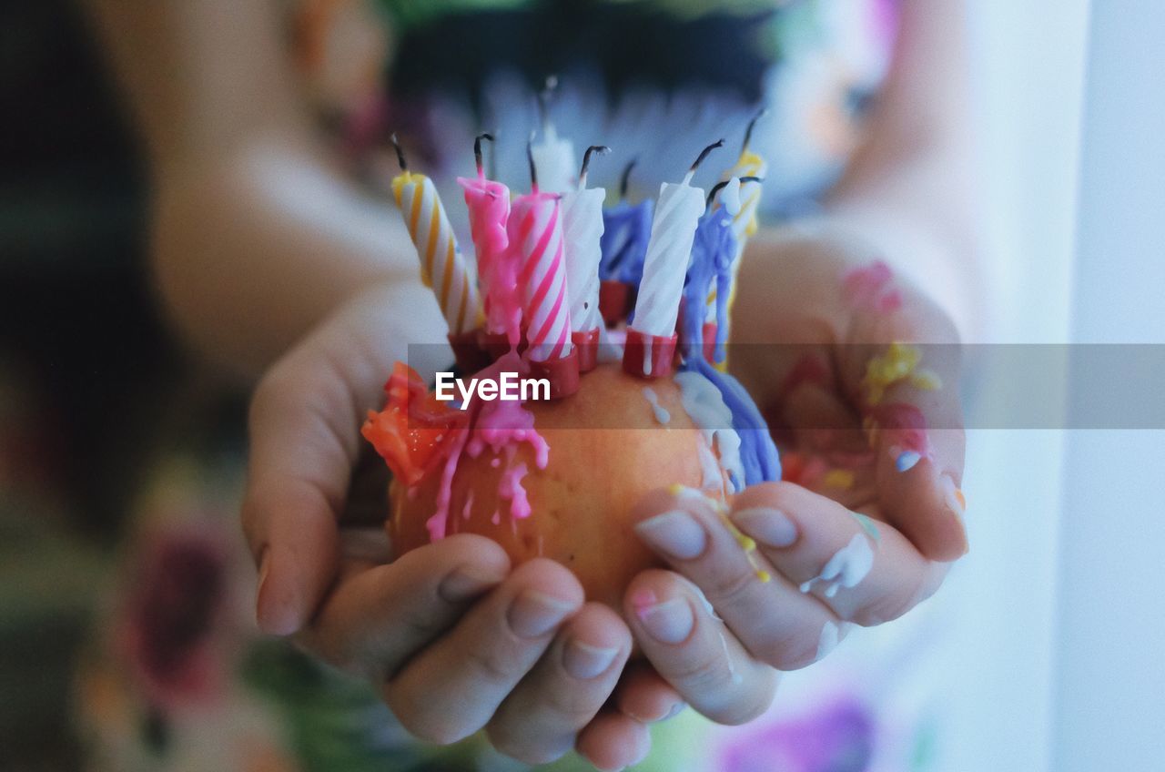 Close-up of hand holding apple with birthday candles