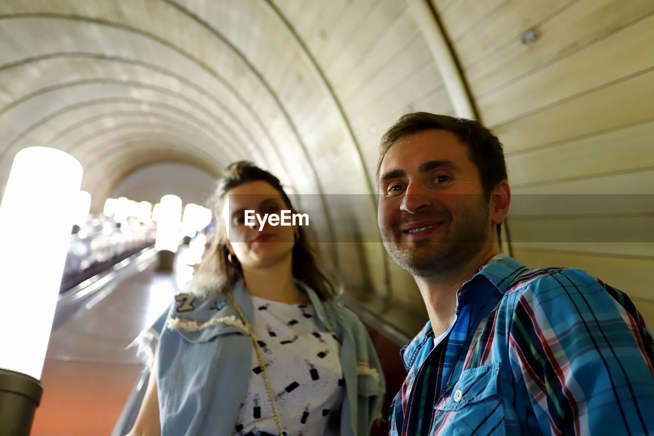 Portrait of smiling couple standing in subway station