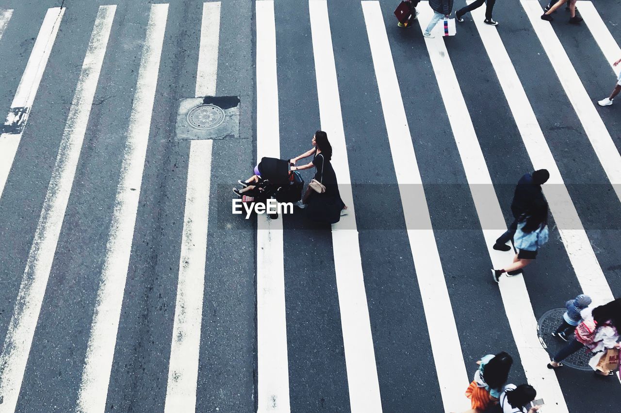 HIGH ANGLE VIEW OF TWO PEOPLE CROSSING ROAD