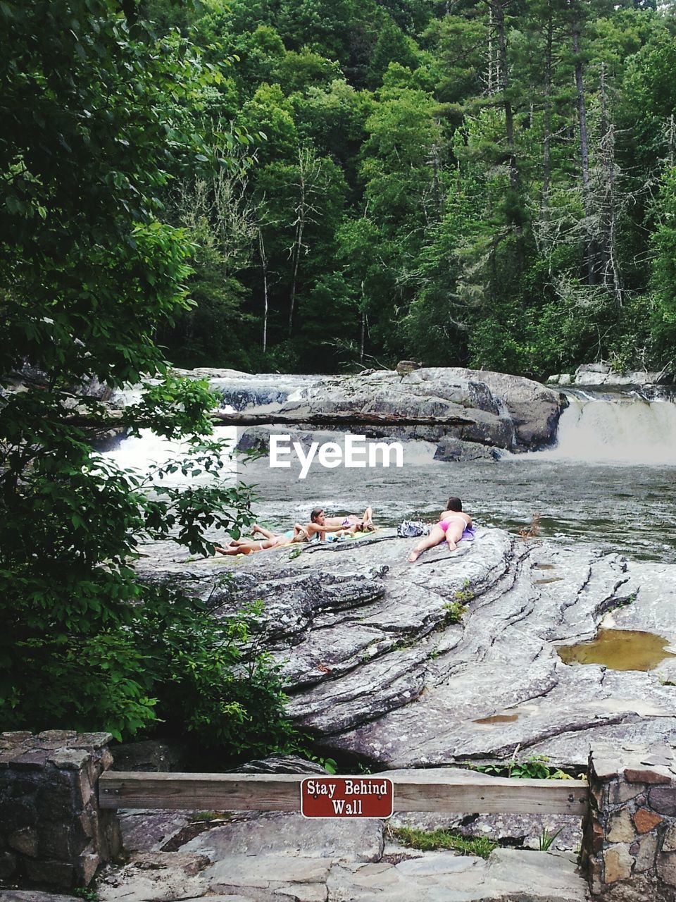 High angle view of people relaxing on rock formation against river