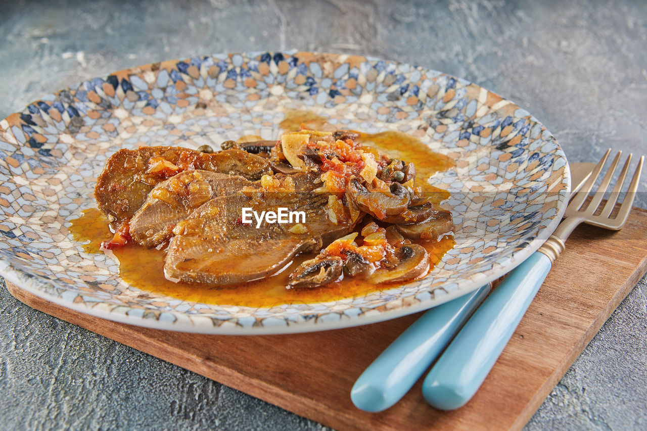 Veal tongue with tomato sauce, mushrooms and capers. french gourmet cuisine