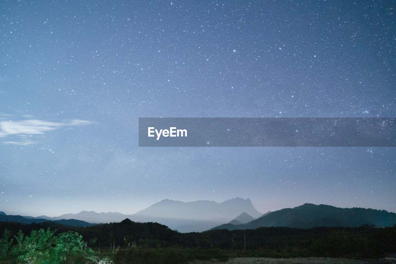 SCENIC VIEW OF MOUNTAINS AGAINST STAR FIELD