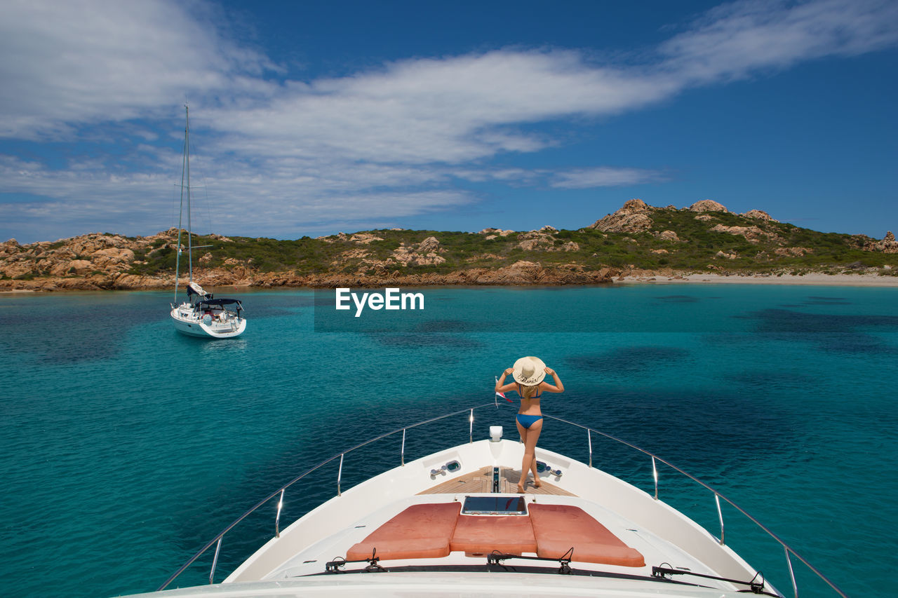 Rear view of woman on yacht boat deck in aegean sea against sky