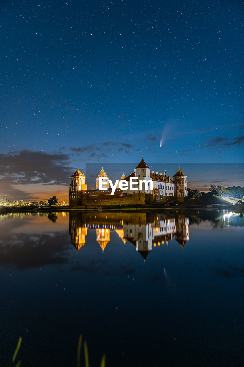Comet neowise in a night landscape. mir castle in belarus. astronomy. 