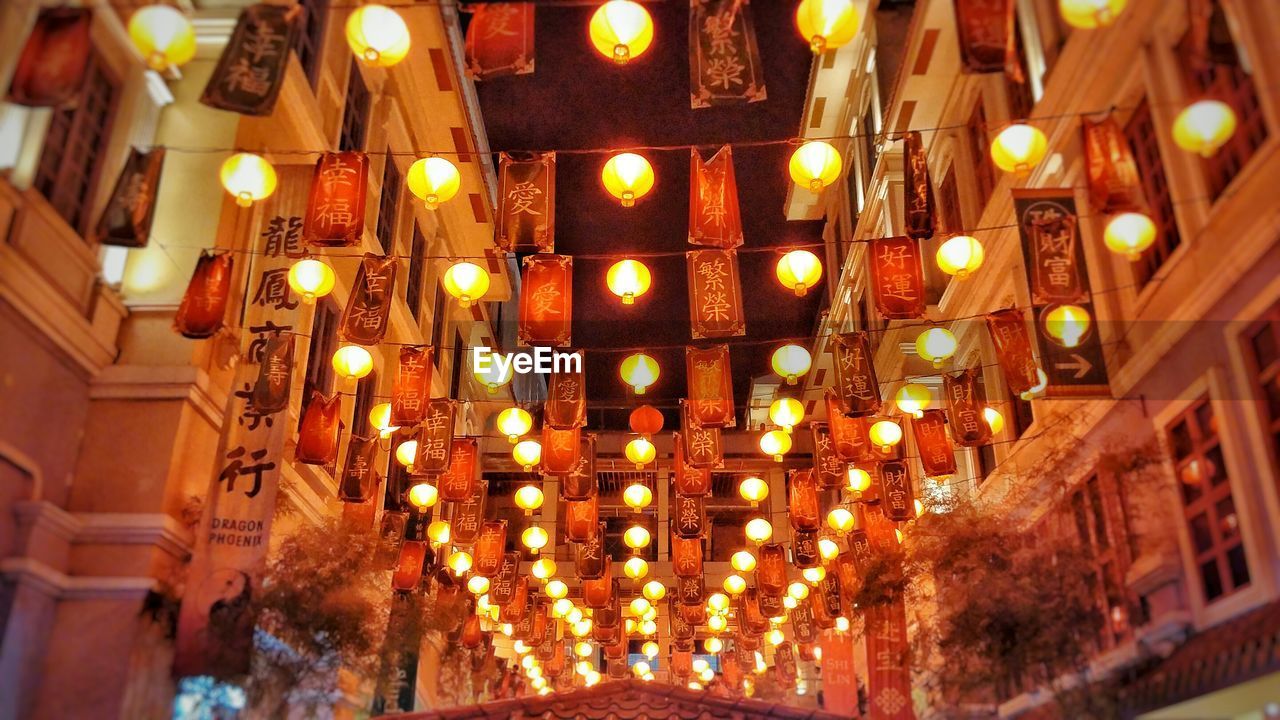 Low angle view of illuminated lanterns amidst buildings at night