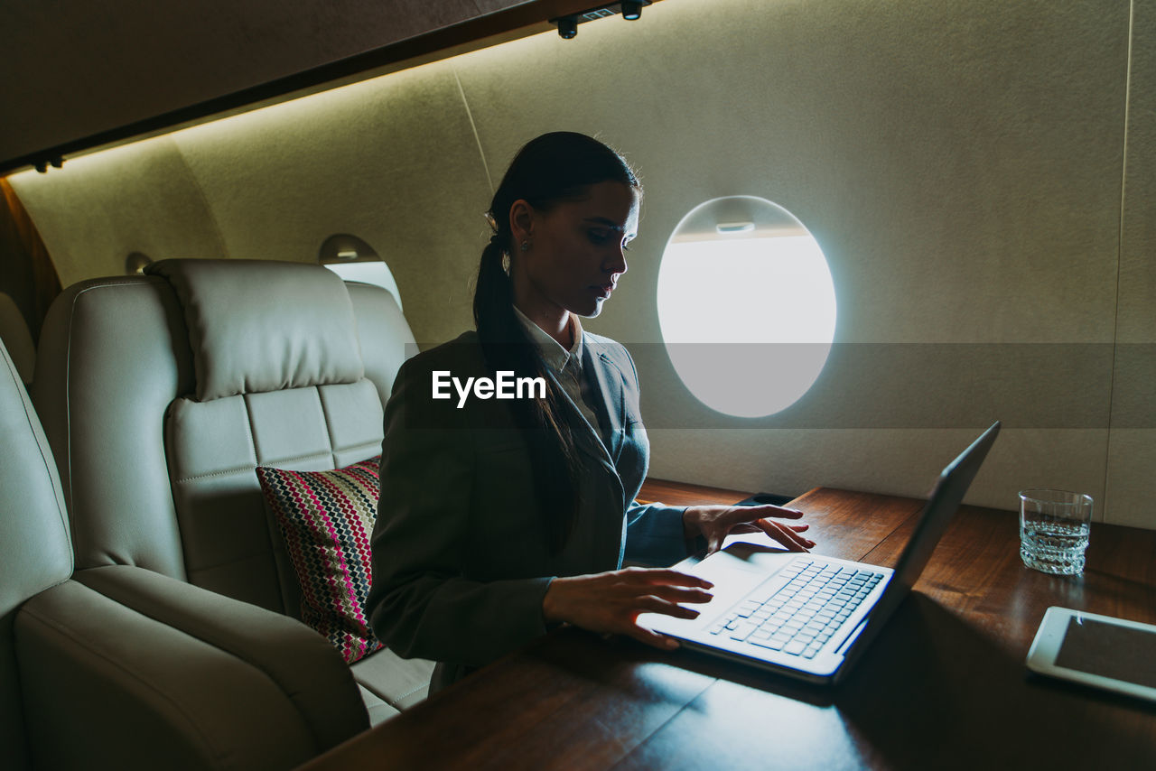 Businesswoman using laptop in airplane